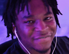 a man with dreadlocks is wearing earbuds and smiling