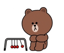 a brown teddy bear is sitting next to a pendulum with red cherries hanging from it .