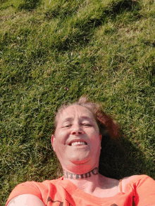 a woman in an orange shirt is laying in the grass