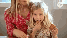 a woman and a little girl are eating chicken nuggets in front of a sign that says " kin "