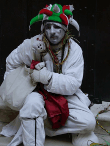 a man dressed as a jester holds a stuffed animal