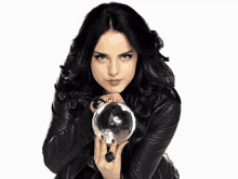 a woman in a leather jacket is holding a clear ball