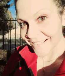 a woman wearing a red jacket and necklace smiles for the camera