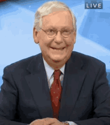 a man wearing a suit and tie is smiling in front of a live sign