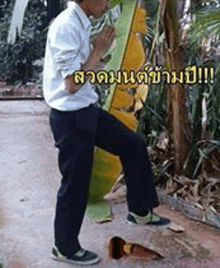 a man in a white shirt and black pants is standing next to a broken shoe .