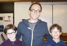 a man wearing glasses is standing next to two boys wearing glasses .