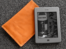 a kindle sits on top of an orange wallet