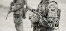 a soldier with a saudi flag on his shirt holds a gun .