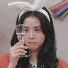 a woman with bunny ears is holding a glass of wine .