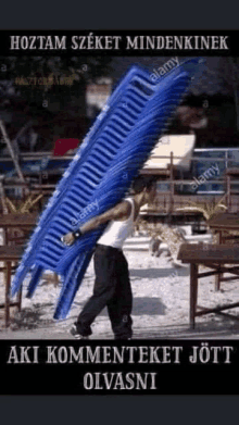 a man is carrying a stack of chairs on his back .