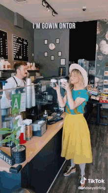 a woman in a yellow skirt is holding a cup of coffee in front of a sign that says a on it