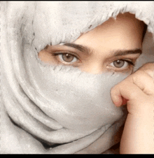 a close up of a woman 's face with a white scarf covering her face