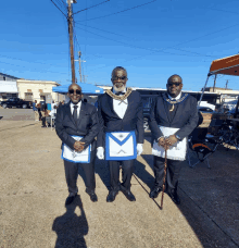 three men in masonic uniforms pose for a picture on a sidewalk