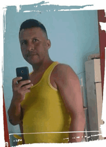 a man in a yellow tank top takes a selfie with his phone