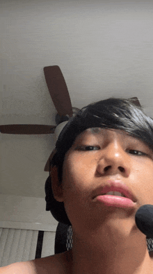 a young man taking a selfie with a ceiling fan behind him