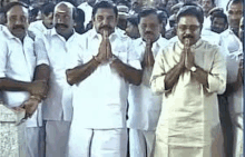 a group of men are standing next to each other with their hands folded in front of a crowd .