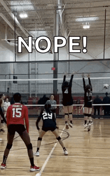 a group of girls are playing volleyball in a gym and one of them is wearing a number 15 jersey .