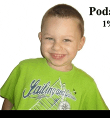 a young boy wearing a green sailing and adventure shirt smiles for the camera