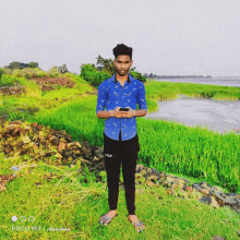 a man in a blue shirt and fila pants stands in a grassy field