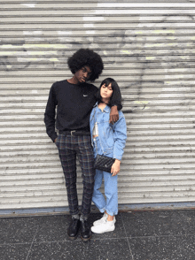 a man and a woman standing next to each other in front of a shutter