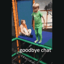 a boy in a green shirt is jumping on a trampoline while a girl sits on the ground behind him