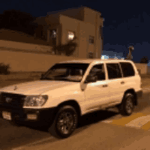 a white suv parked on the side of the road at night