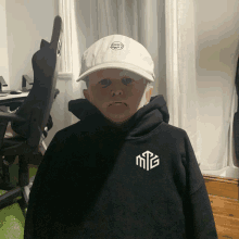 a boy wearing a white hat and a black hoodie with the letter mtg on it