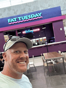 a man is standing in front of a fat tuesday restaurant