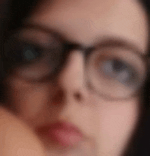 a blurry picture of a woman wearing glasses looking at the camera .