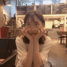 a woman wearing glasses is sitting in front of a restaurant menu that says lunch set