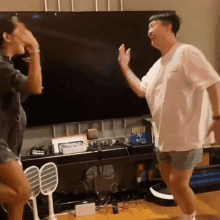 a man and a woman are dancing in front of a television .