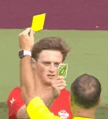 a man is holding a yellow card over his head and another man is holding a card .