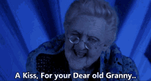 an elderly woman with glasses and a blue sweater says a kiss for your dear old granny