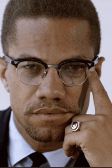 a close up of a man wearing glasses and a ring