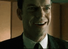 a man in a suit and tie is smiling in a dark room .