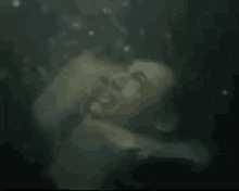 a man is swimming underwater in a dark room with bubbles coming out of his mouth .