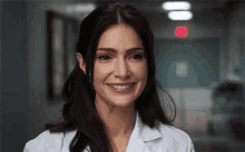 a close up of a woman in a lab coat smiling .