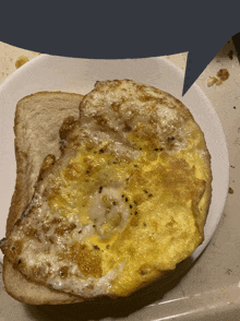 a white plate topped with a slice of bread and a fried egg