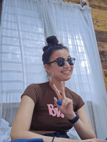 a woman wearing sunglasses and a brown crop top with the letter b on it