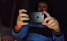 a man is taking a selfie with his cell phone in a dark room .