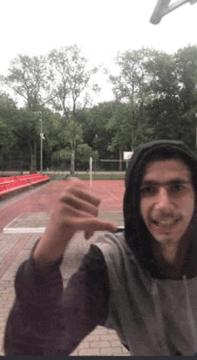 a man in a hoodie is standing in front of a basketball court .