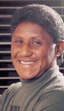 a close up of a man wearing a green turtleneck shirt smiling .