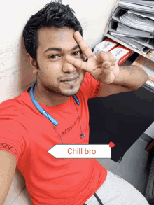 a man wearing a red shirt that says chill bro giving a peace sign