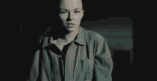 a woman with a bald head is standing in a dark room .