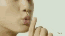 a woman is holding her finger to her mouth .