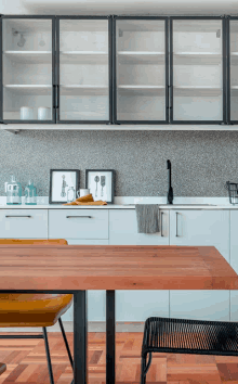 a kitchen with white cabinets and a wooden table with a yellow chair