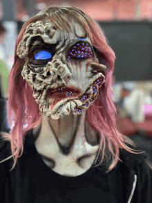 a woman with pink hair is wearing a scary mask on her face