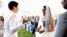 a bride and groom are standing next to each other in front of a crowd at their wedding ceremony .