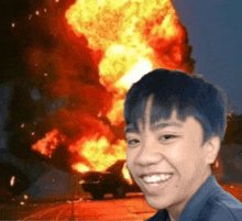 a young boy is smiling in front of a large explosion .