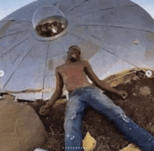 a man is laying on the ground in front of a ufo .